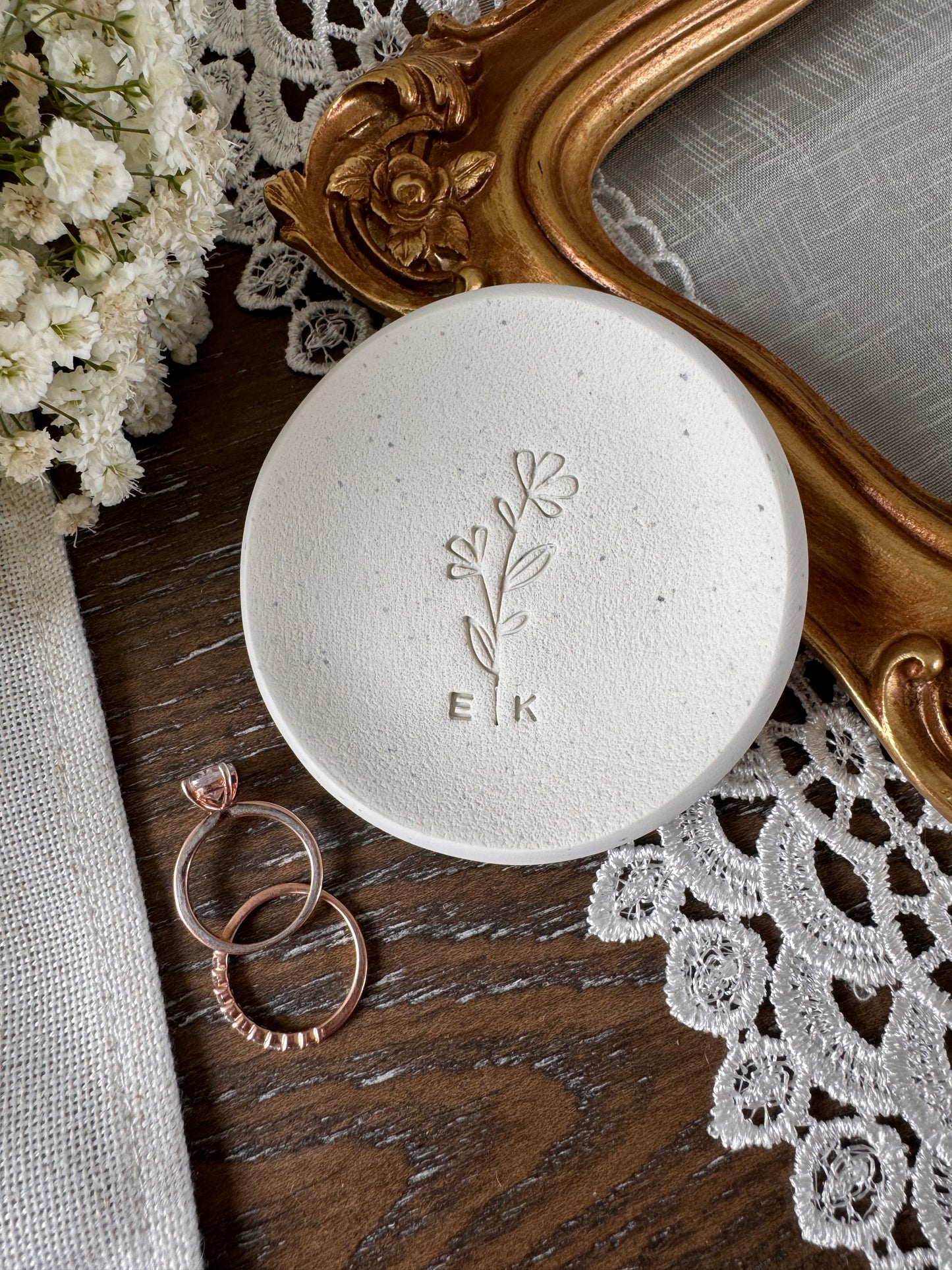 simple white speckled ring dish with flower embossed design in center, personalized initials