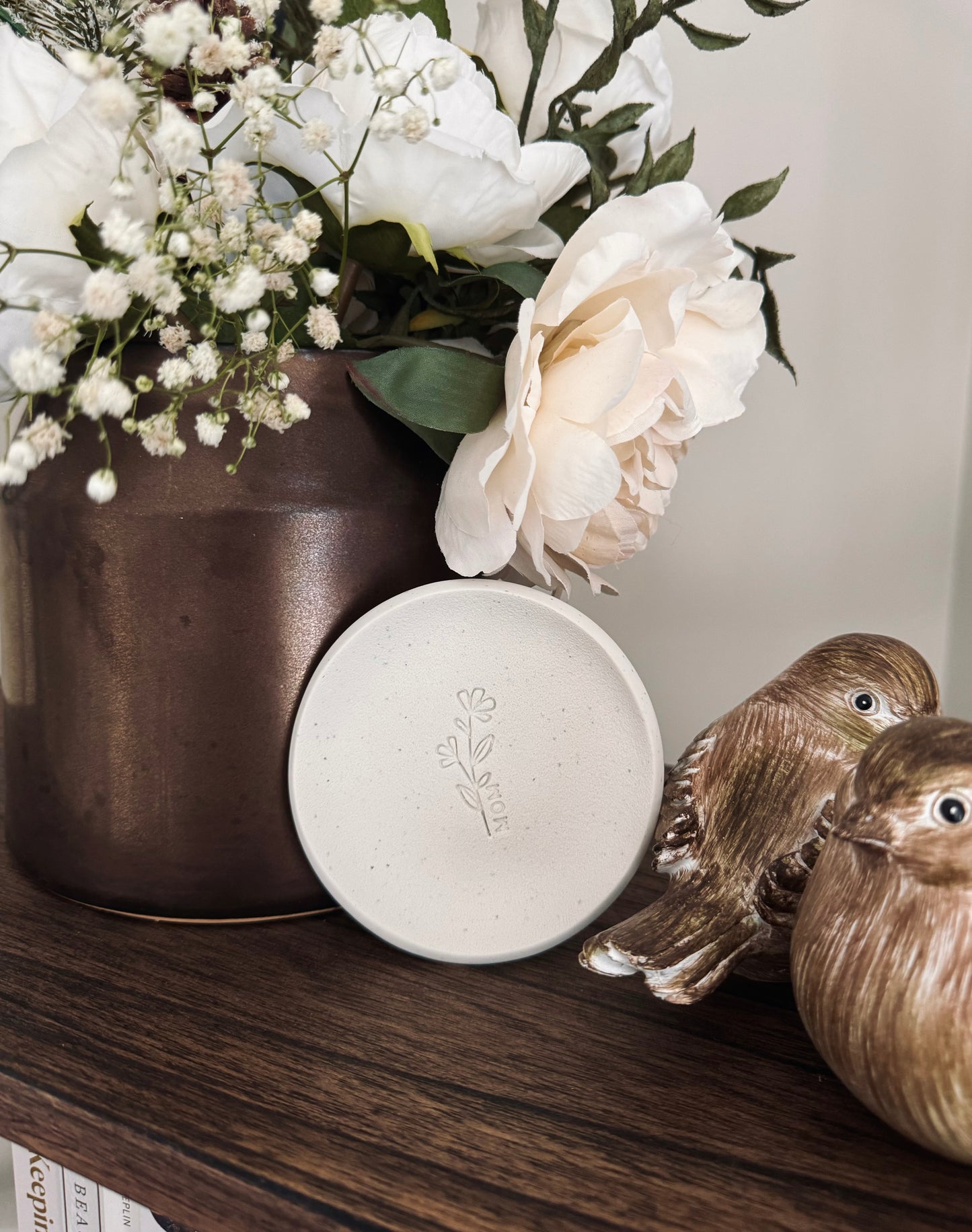 simple ring dish made of speckled white clay with floral embossed design, perfect photography prop
