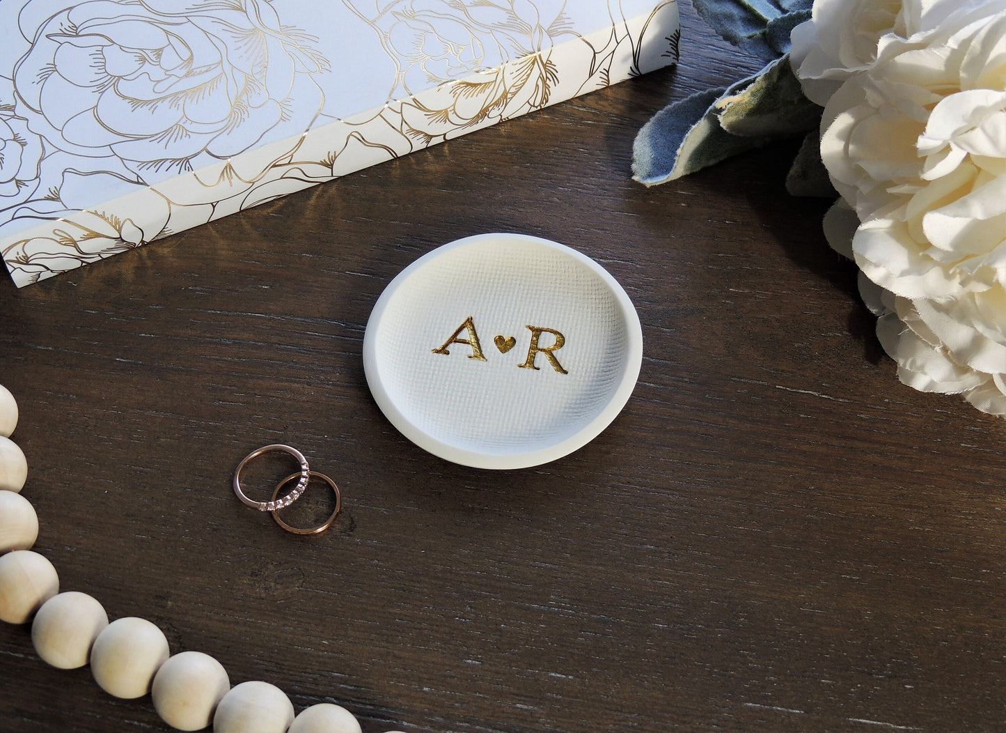 white ring dish with large initials in center in gold foil