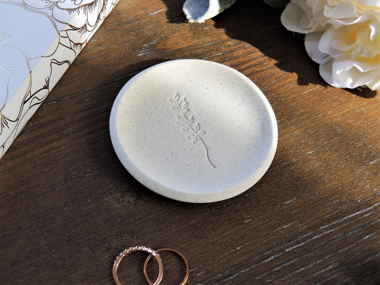 white speckle ring dish with leaf branch in center