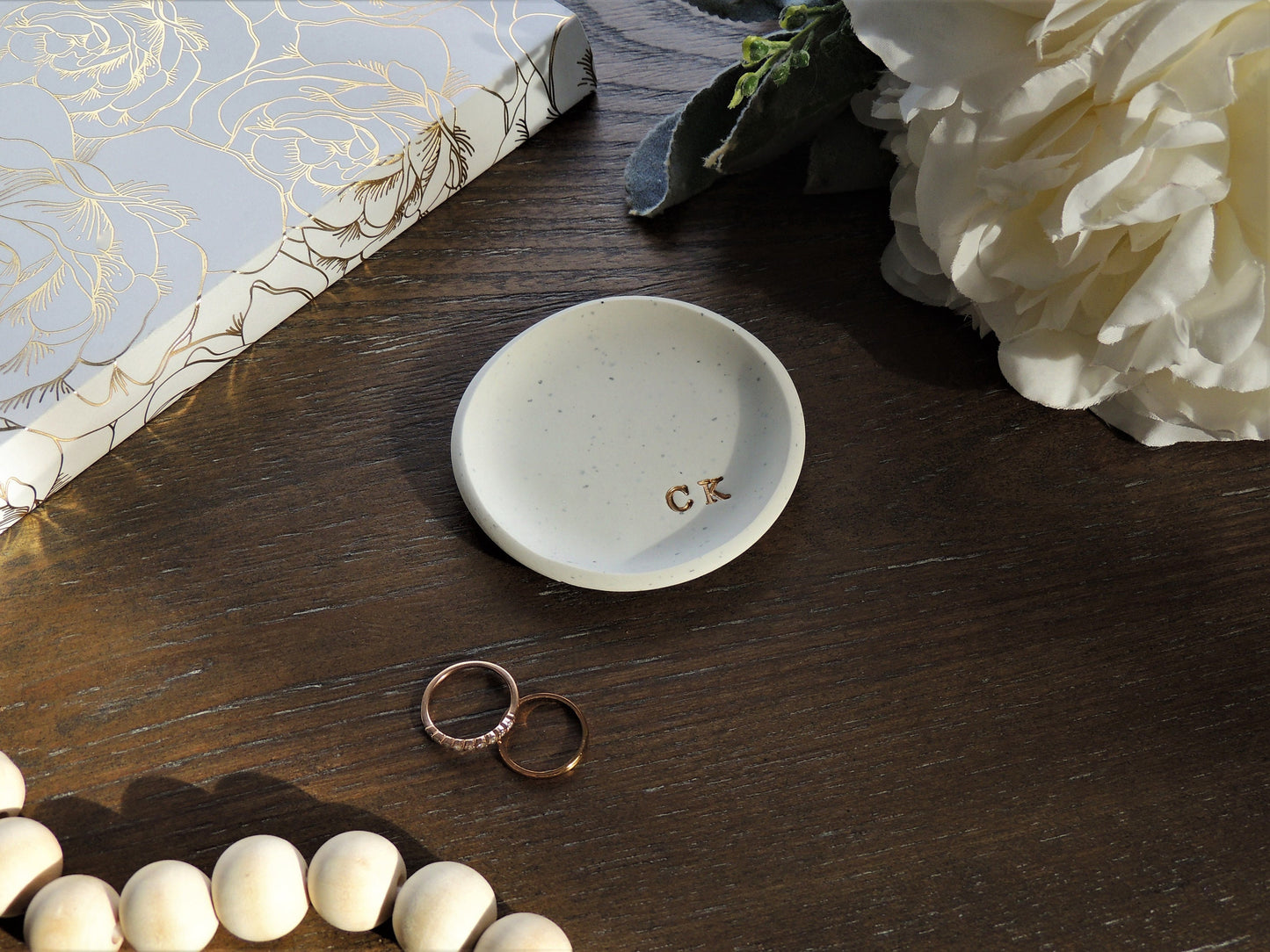 simple white speckled clay ring dish with initials in bottom right in gold foil
