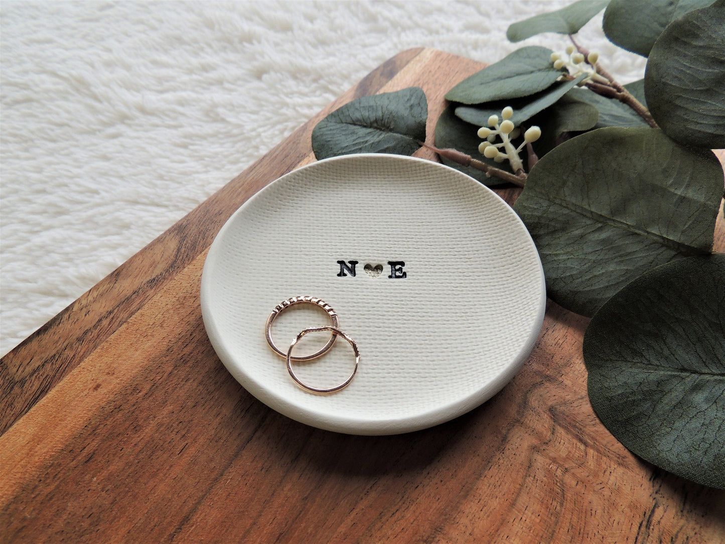 ring dish made of white clay with simple black initials in the center