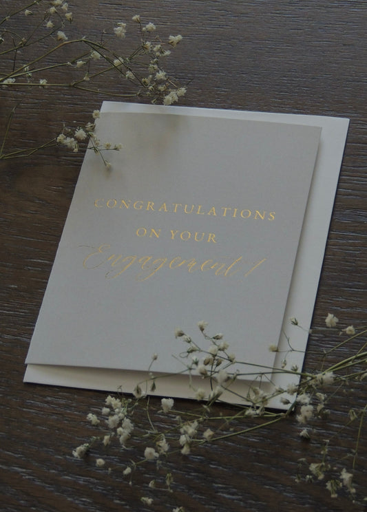 ivory card with gold foil lettering "congratulations on your engagement" simple