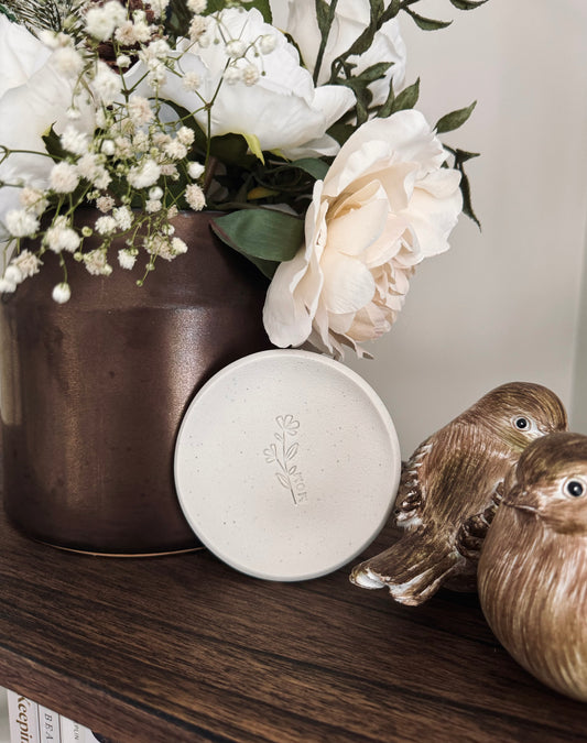 simple ring dish made of speckled white clay with floral embossed design, perfect photography prop