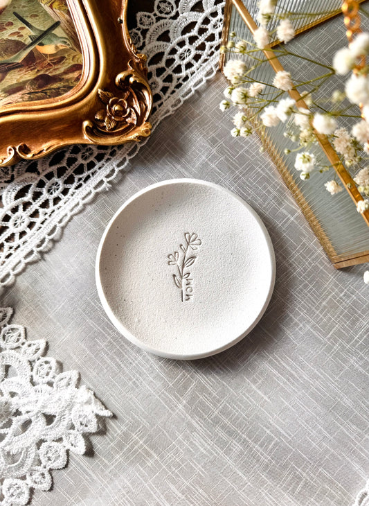 simple ring dish made of speckled white clay with floral embossed design, perfect flat lay prop