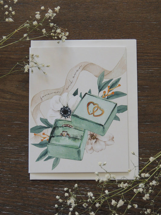 water color wedding card with florals, ring box and ribbon with words "forever and ever"