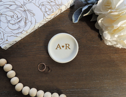 white ring dish with large initials in center in gold foil
