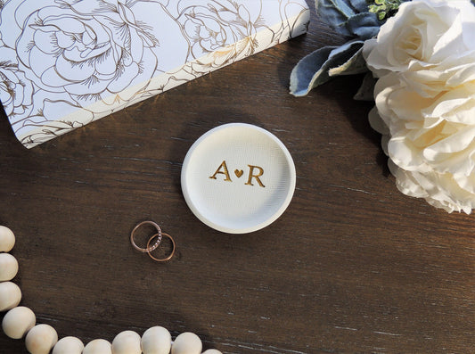 white ring dish with large initials in center in gold foil