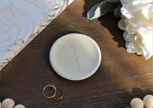 white speckle ring dish with leaf branch in center