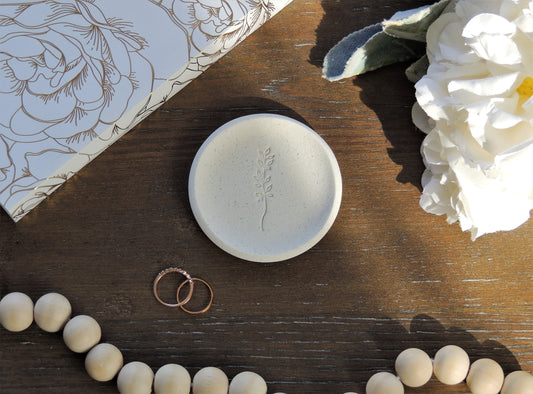 white speckle ring dish with leaf branch in center