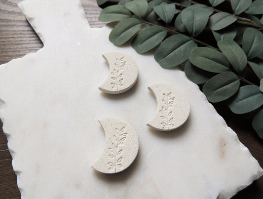 white magnet, crescent moon shaped with olive leaf design