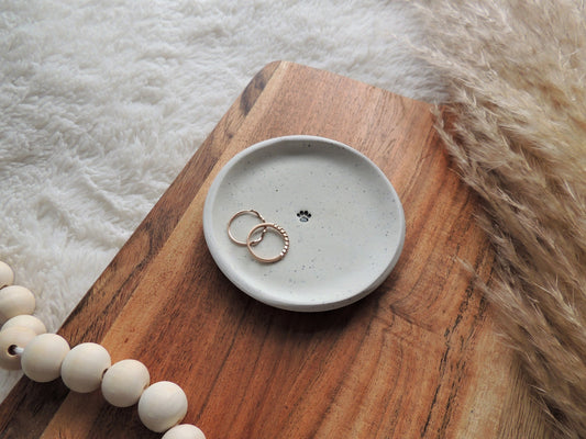 white clay speckled ring dish with black paw print in center