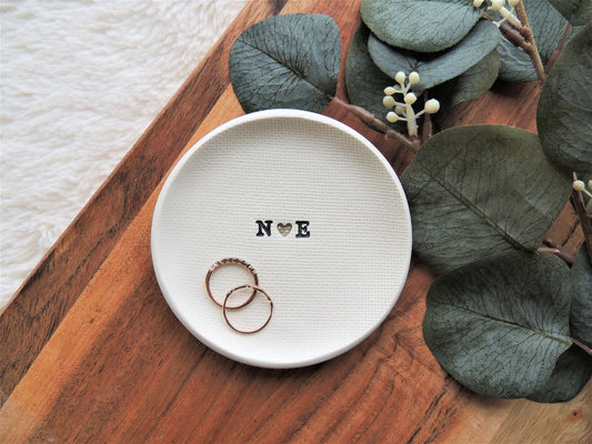 ring dish made of white clay with simple black initials in the center
